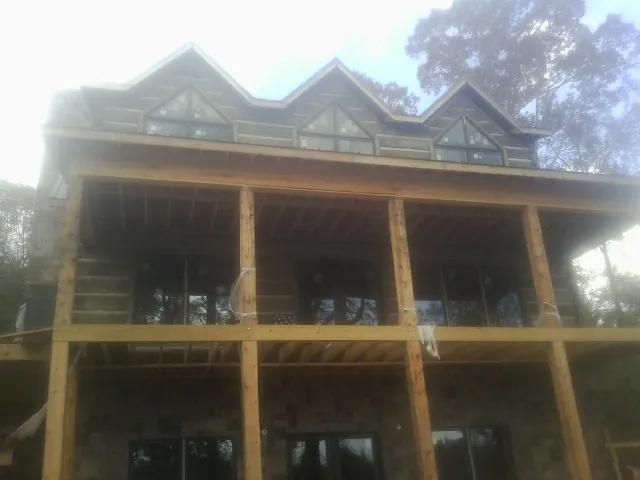 Dormers and porch framing on a large log home under construction — Roof Coating work by our crew in Modoc