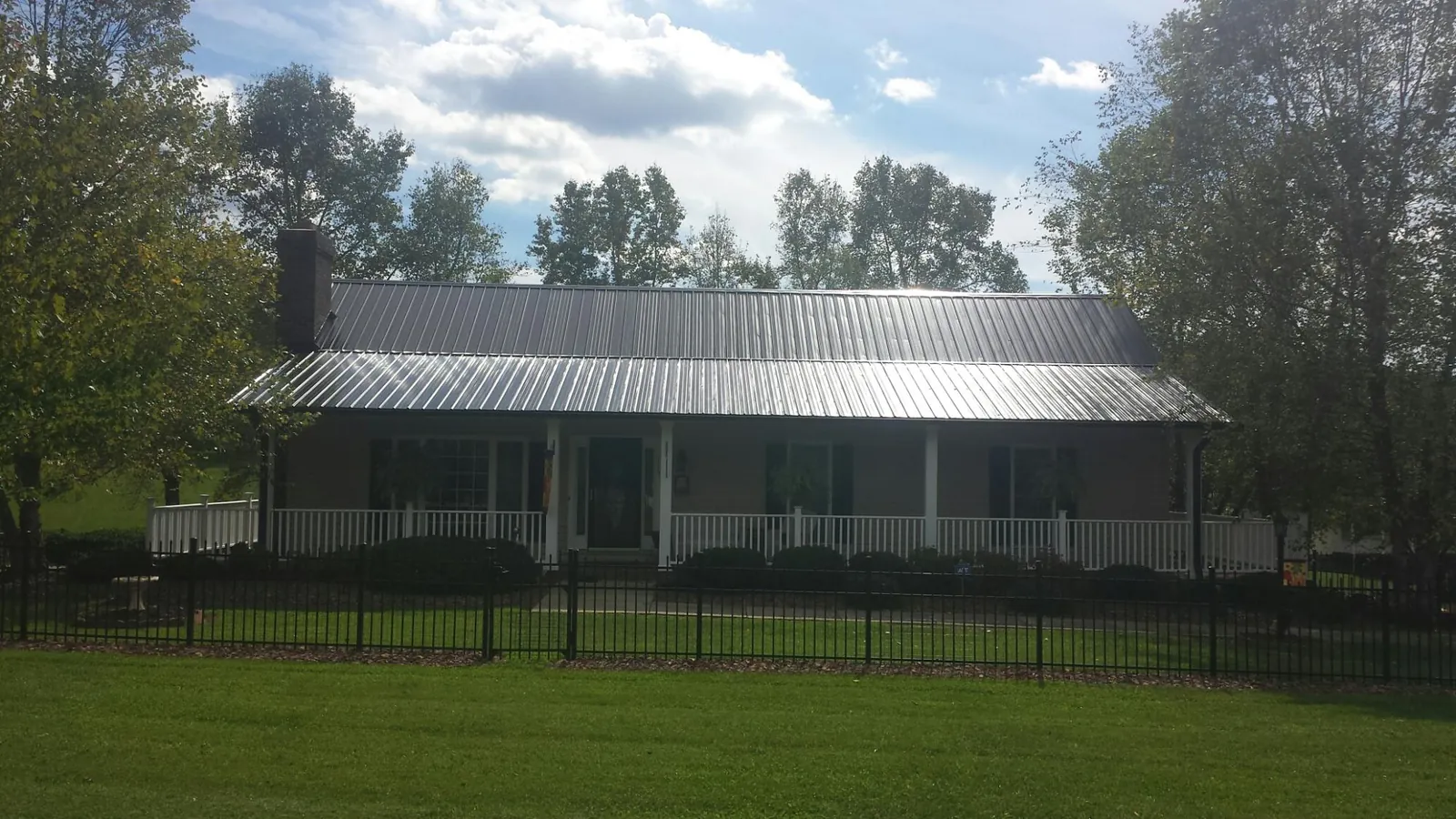 Gray metal roof on a brick ranch with a full width front porch — Gutter Guard Installation work by our crew in Modoc