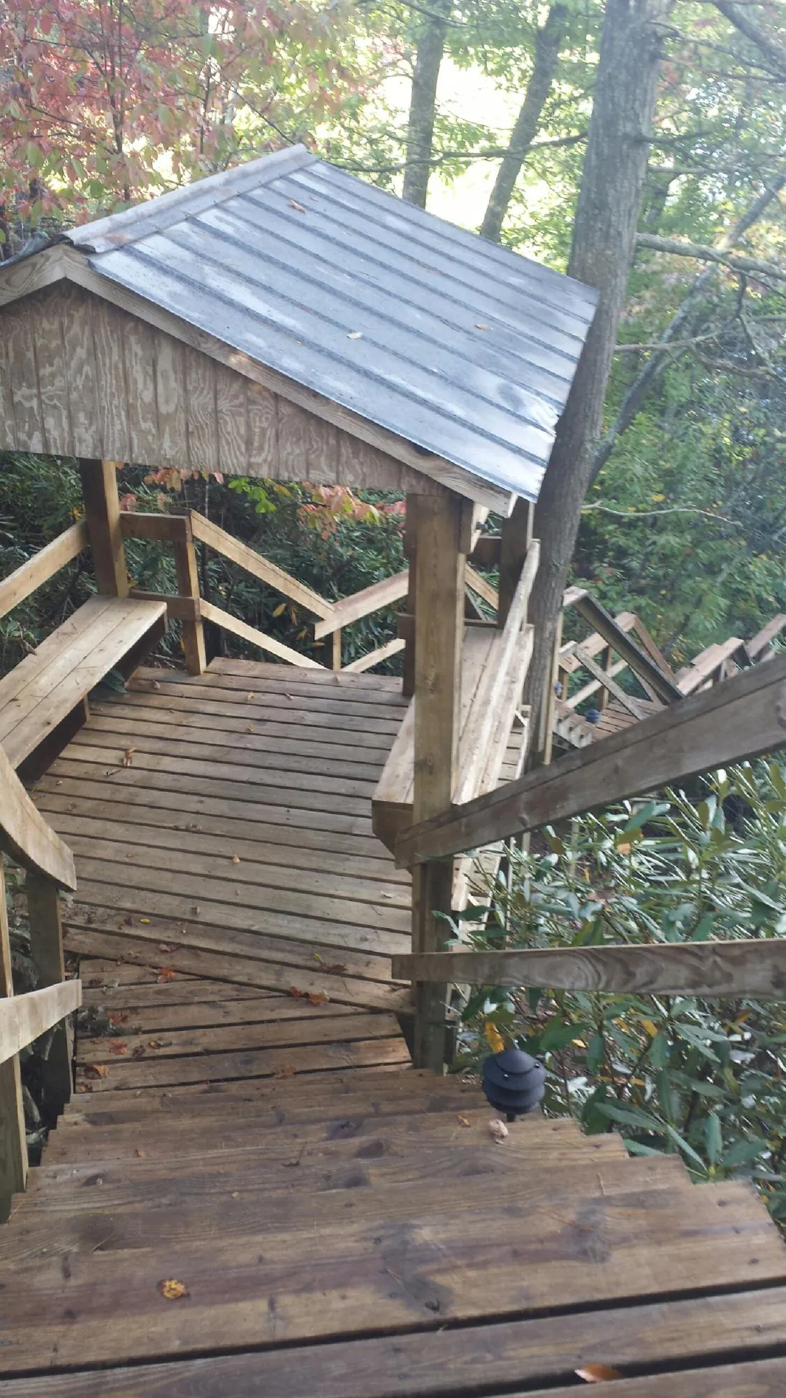 Metal roofed shelter over wooden steps on a wooded walkway — Skylight Repair & Installation work by our crew in Modoc