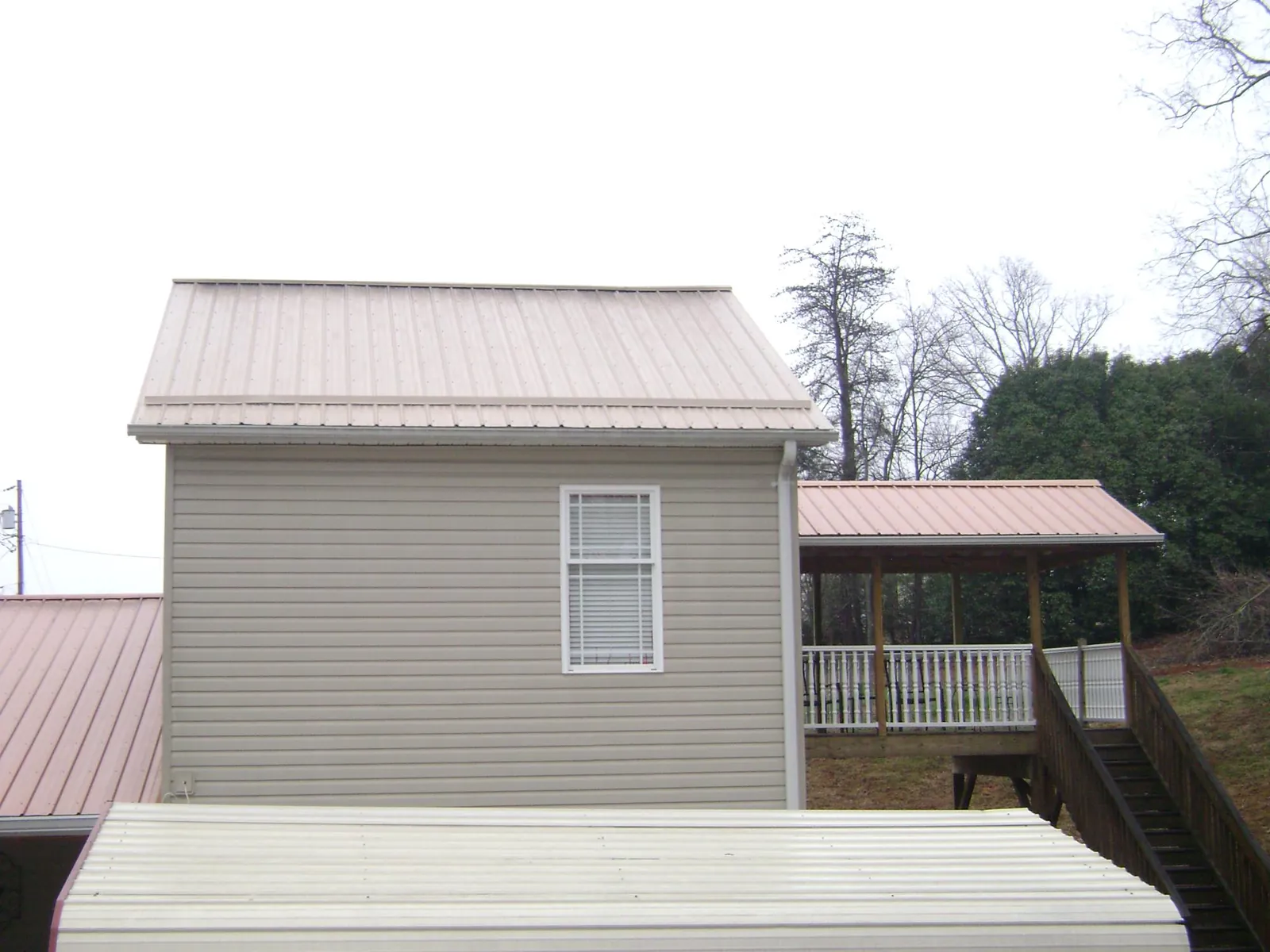 Tan metal roofs on a two story addition and attached porch, from a Roof Replacement job in Modoc