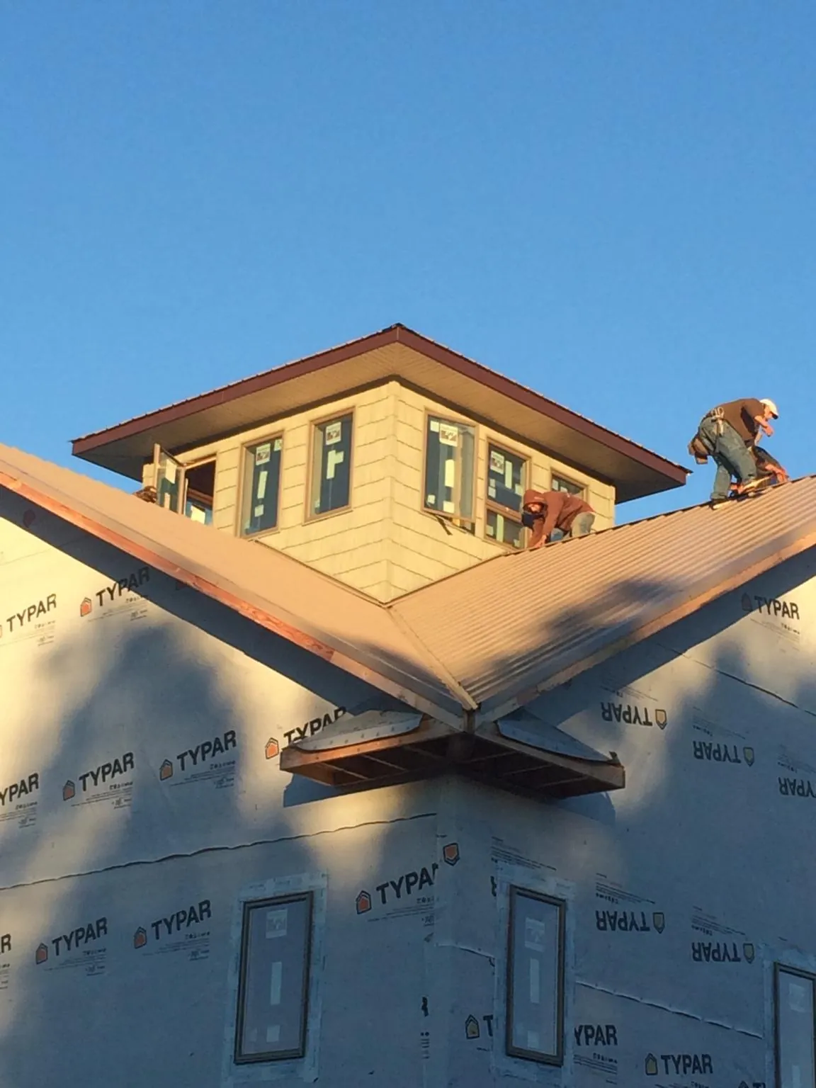 Roofers working around a rooftop cupola on a new metal roof at sunset — Roof Waterproofing in Modoc by Roofing Brothers